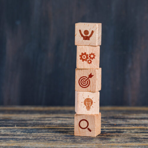 Business strategy concept with wooden cubes on wooden and grunge background side view.